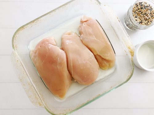 Chicken Breasts in a clear dish getting ready to be sprinkled with everything bagel seasoning.