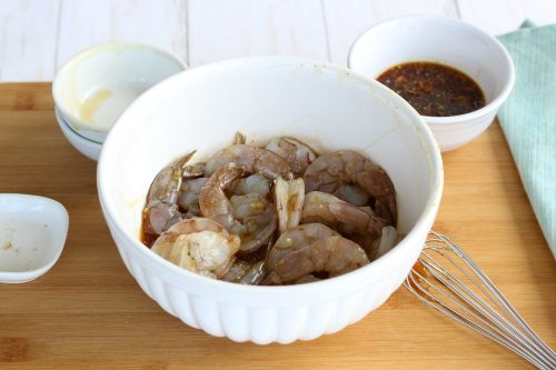 Image shows the honey garlic shrimp in a bowl marinating in the easy garlic shrimp sauce. 
