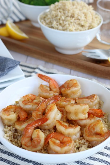 Close up image of the final easy shrimp recipes, garlic shrimp over brown rice with more rice in the background ready to eat. 