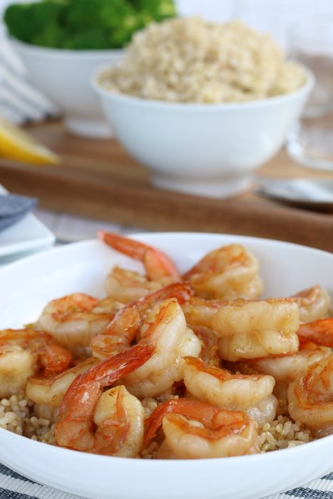 Beautiful shot of the final product of how to cook shrimp. The honey garlic shrimp are on top of a bowl of rice, an easy shrimp recipe ready to eat! 